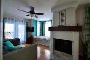 a living room with a fireplace and a ceiling fan at Auberge Fleurs de Lune in La Malbaie