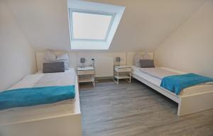 two beds in a small room with a window at CityPension-Vreden in Vreden