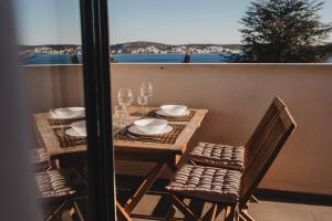 einen Tisch mit Stühlen und Weingläsern auf dem Balkon in der Unterkunft 3in1 Holiday Home in Rogoznica