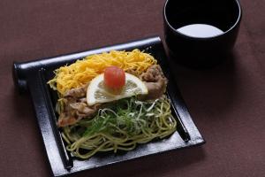 a plate of noodles and meat with a lemon on top at Dormy Inn Premium Shimonoseki in Shimonoseki