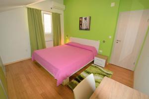 1 dormitorio con cama rosa y paredes verdes en Villa Rosa, en Dubrovnik