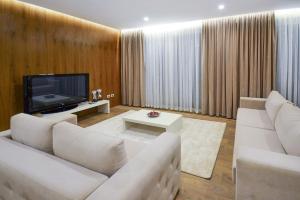ein Wohnzimmer mit weißen Sofas und einem TV in der Unterkunft Hotel Bora Bora velipoja in Velipojë