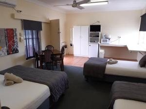 a room with two beds and a table and a kitchen at Inverell Motel in Inverell