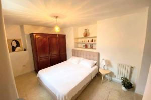 a bedroom with a white bed and a wooden cabinet at Cosy 2 pièces charmant et spacieux in Tunis