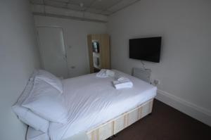 sypialnia z białym łóżkiem i telewizorem z płaskim ekranem w obiekcie Central Comfort Rooms w Londynie