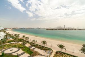 a beach with palm trees and palm trees at GLOBALSTAY Holiday Homes - Sarai Apartments, Beach, Pool, Gym in Dubai