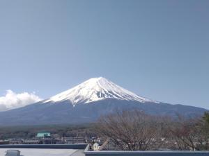 a snow covered mountain in the distance with a city at Fuji Mountain Resort Hotel in Fujikawaguchiko