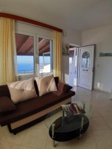 uma sala de estar com um sofá e uma mesa de vidro em Roussa's View Apartments em Sitia