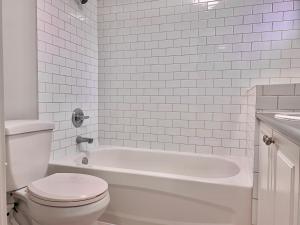 a white bathroom with a toilet and a bath tub at Lisa’s lovely little house in Vancouver