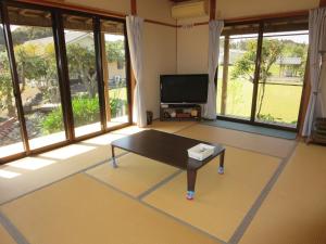 a living room with a table and a flat screen tv at Guesthouse Suzukaze in Shibushi