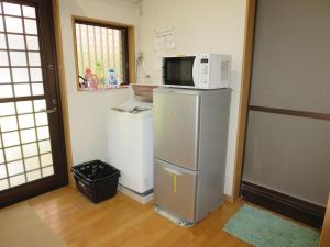 a kitchen with a microwave on top of a refrigerator at Guesthouse Suzukaze in Shibushi