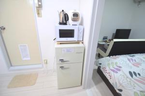 宮崎市にあるComfort CUBE PHOENIX MIYAZAKIの小さな客室で、冷蔵庫の上に電子レンジが備わります。