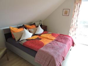 uma cama com cobertores coloridos e almofadas em Ferienhaus - Haus Winterberg em Winterberg