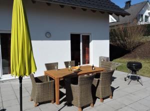 a wooden table with chairs and a yellow umbrella at Ferienhaus - Haus Winterberg in Winterberg