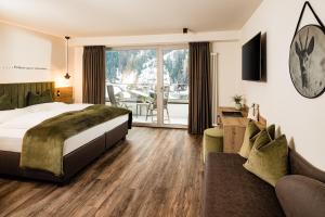 une chambre d'hôtel avec un lit et un canapé dans l'établissement Hotel Touring Dolomites, à Santa Cristina Valgardena