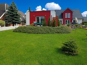 czerwono-biały dom z zielonym dziedzińcem w obiekcie Mach mal Pause w mieście Wyspa Poel