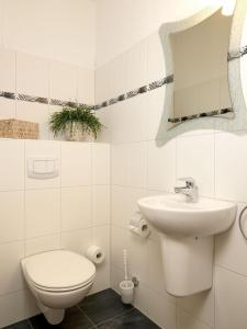 biała łazienka z toaletą i umywalką w obiekcie Reihenhäuser Timmendorf Strand Haus Sonnenaufgang w mieście Wyspa Poel