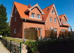duży ceglany dom z pomarańczowym dachem w obiekcie Reihenhäuser Timmendorf Strand Haus Sonnenaufgang w mieście Wyspa Poel