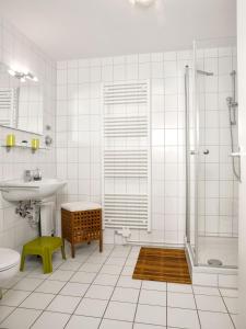 La salle de bains blanche est pourvue d'un lavabo et d'une douche. dans l'établissement Appartements Am Reiterhof Seepferdchen, à Timmendorfer Strand