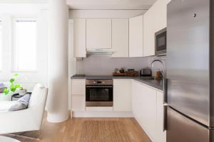 a kitchen with white cabinets and a stainless steel refrigerator at 2ndhomes Design Apartment in Kamppi in Helsinki