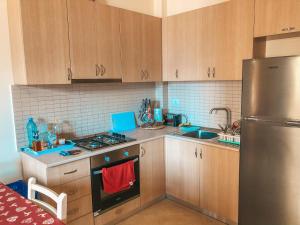 eine Küche mit Holzschränken und einem Kühlschrank aus Edelstahl in der Unterkunft MiMi's Beach Apartment in Vlorë