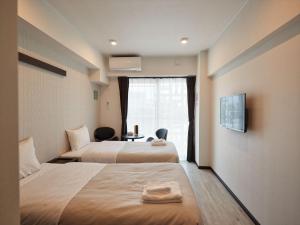 ein Hotelzimmer mit 2 Betten und einem Fenster in der Unterkunft アルセ琉球ハーバーステイ in Urazoe