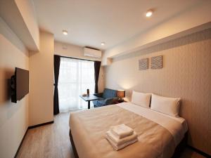 ein Hotelzimmer mit einem großen Bett und einem Stuhl in der Unterkunft アルセ琉球ハーバーステイ in Urazoe