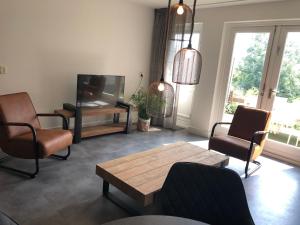 sala de estar con sillas, mesa y TV en Grasse 140 - Kustpark Village Scaldia, en Hoofdplaat