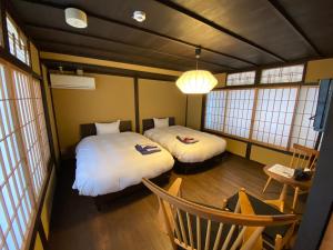 een kamer met 2 bedden, een stoel en ramen bij Rinn Shijo Takasegawa in Kyoto