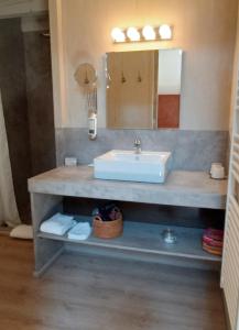 a bathroom with a sink and a mirror at Des Lits Sur La Place in Hérépian