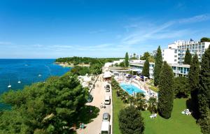 a view of a resort with a swimming pool and the ocean at Hotel Zorna Plava Laguna in Poreč