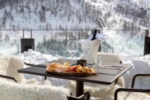 a table with a plate of food and wine glasses at Bergman Mountain Hotel in Breuil-Cervinia