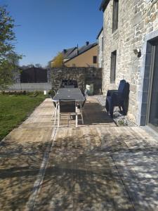 a table and chairs on a patio with a building at Gîtes du tellin in Couvin