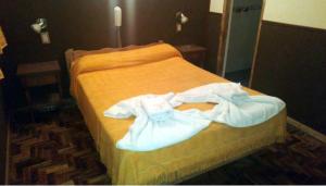 Hotel Oasis في مار ديل بلاتا: غرفة نوم عليها سرير وملابس بيضاء