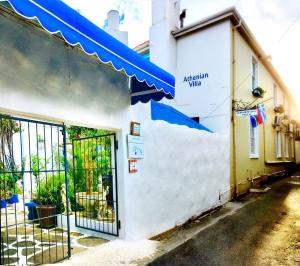 un bâtiment blanc avec un auvent bleu dans une rue dans l'établissement Athenian Villa, à Caledon