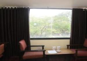 帕格爾布爾的住宿－Hotel Rajhans International，客房设有带桌椅的窗户和带窗户的书桌。