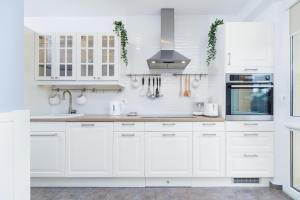 a white kitchen with white cabinets and appliances at Apartments Obopólna Cracow by Renters in Krakow