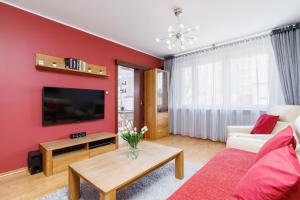 uma sala de estar com uma parede vermelha em Apartments Obopólna Cracow by Renters em Cracóvia