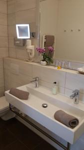 a bathroom with a sink with a large mirror at Landhotel Böld Oberammergau in Oberammergau