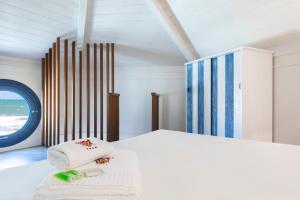 a white bedroom with a bed and a window at Arìa Residenze d'aMare in Crotone