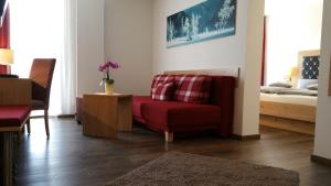 a living room with a red chair and a bed at Landhotel Böld Oberammergau in Oberammergau