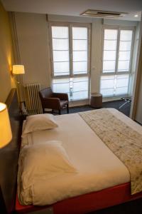 um quarto com uma cama, uma cadeira e janelas em Grand Hôtel d'Orléans em Toulouse