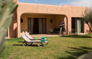 two people standing outside of a house with a chair at Oasis lodges in Marrakesh
