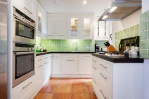 a kitchen with white cabinets and green tiles at Veeve - South Kensington Garden Apartment in London