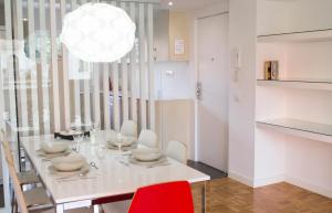 a dining room with a white table and a red chair at Happy People Maragall in Barcelona