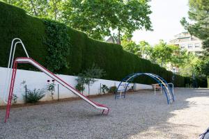 an empty playground with two swings and a slide at Happy People Maragall in Barcelona