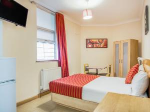 1 dormitorio con 1 cama, TV y ventana en Lovely Studio in London with Patio en Londres