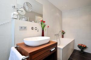 a bathroom with a white sink and a bath tub at Landhotel Böld Oberammergau in Oberammergau