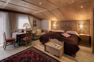 a bedroom with a large bed and a table and a desk at Hotel La Perla: The Leading Hotels of the World in Corvara in Badia