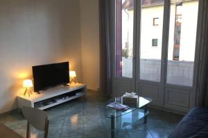 een woonkamer met een flatscreen-tv en een tafel bij LES ÎLES - Parking, Balcon, Netflix & PS4! in Annecy